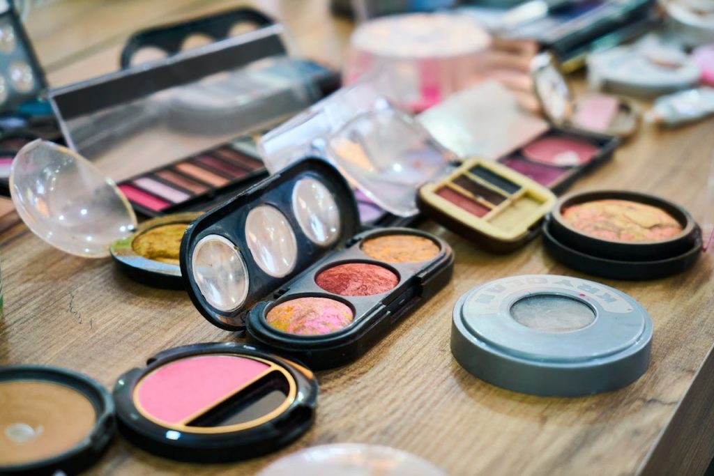 pexels-photo-3148938 A variety of colorful makeup palettes and cosmetics organized on a wooden table.