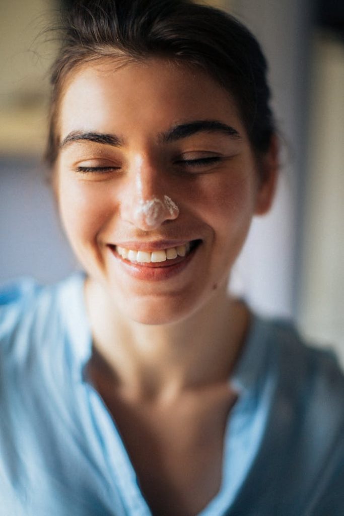 pexels-photo-3893754 Close-up portrait of a smiling woman with cream on her nose.