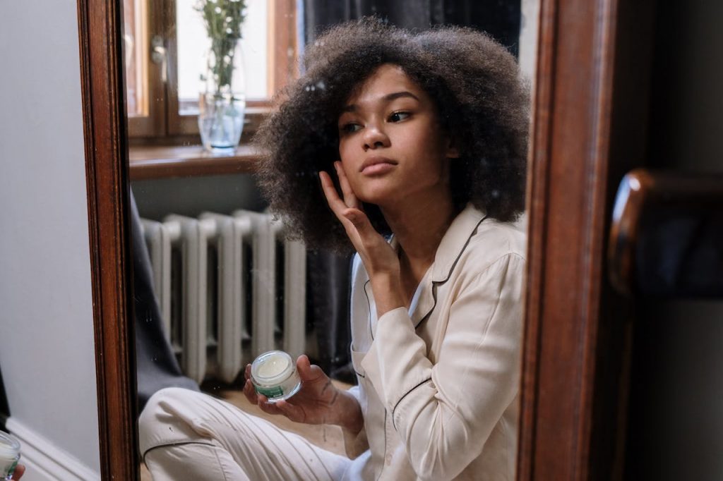 pexels-photo-4046314 A woman applies skincare cream in a cozy home environment during her morning routine.