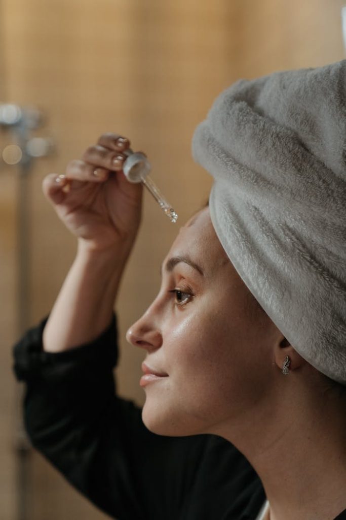 pexels-photo-4612159 Close-up side view of a woman applying skincare serum with a dropper, promoting beauty routine.