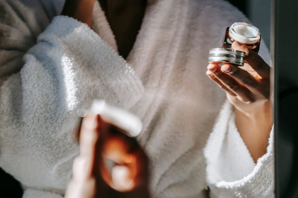 pexels-photo-5938255 Woman in bathrobe applying skincare cream for a calm morning routine.